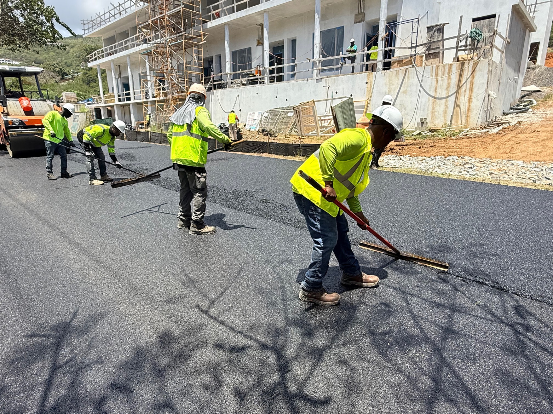 Crew placing and finishing fresh asphalt pavement at a construction site